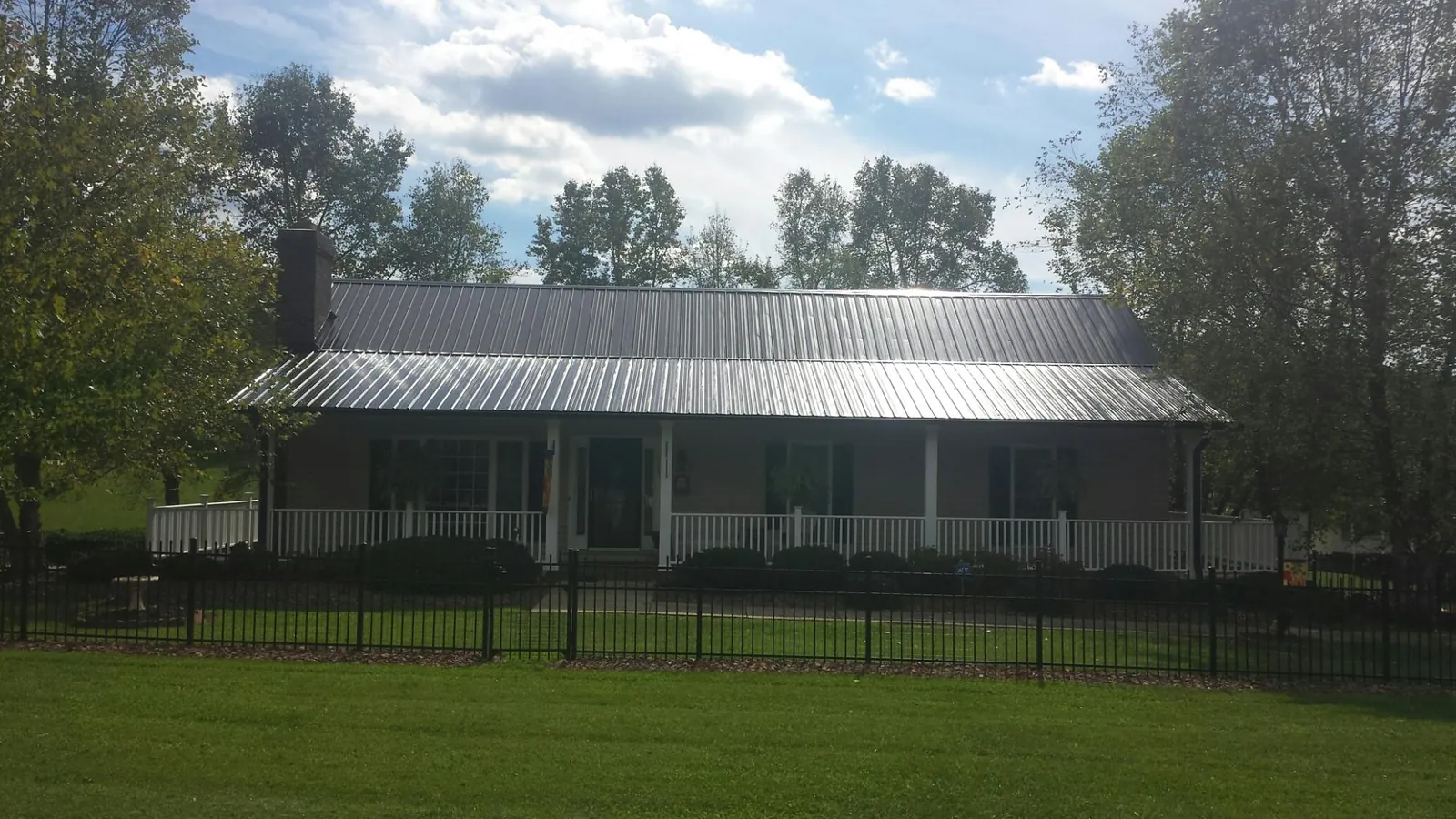 Gray metal roof on a brick ranch with a full width front porch — Gutter Guard Installation work by our crew in Prospect
